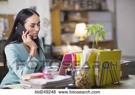 Stock Photo - Thai transgender businesswoman talking on cell phone in office. Fotosearch