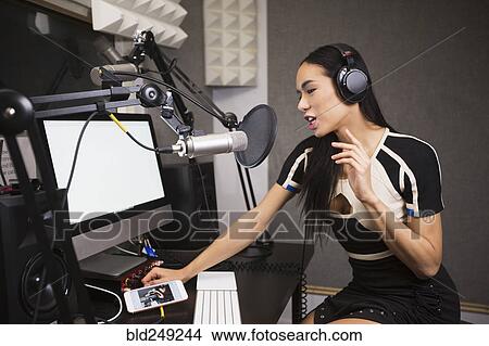 Picture - Thai transgender woman using computer and microphone. Fotosearch