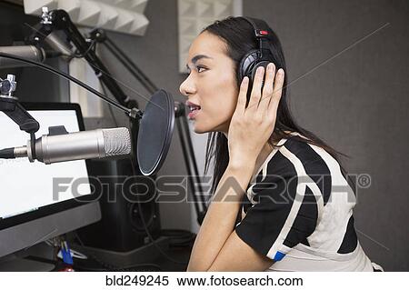 Stock Photography - Thai transgender woman using headphones and microphone. Fotosearch