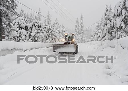 Stock Photo - Tractor with snow plow driving on remote road. Fotosearch