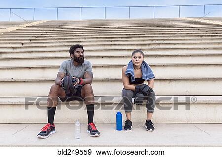 Stock Photo - Trainer and woman resting on bleachers. Fotosearch