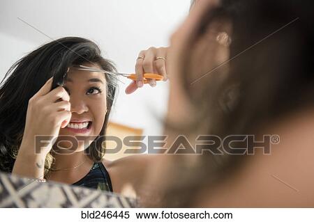 Uncertain Mixed Race woman cutting bangs with scissors View Large Photo Image Stock Photography - Uncertain Mixed Race woman cutting bangs with scissors. Fotosearch