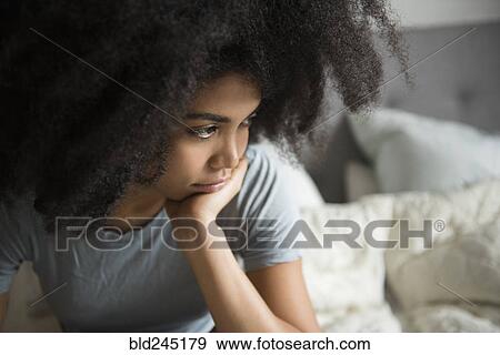 Stock Photo - Unhappy African American woman sitting in bed. Fotosearch