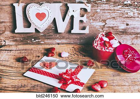 Stock Image - Valentine card and gift box near love carving. Fotosearch