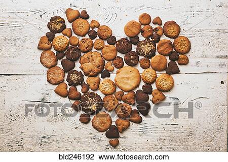 Stock Image - Variety of cookies on wooden table in heart-shape. Fotosearch