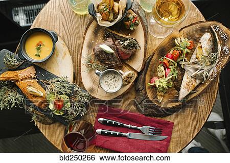Stock Photograph - Variety of meat and fish on table with wine. Fotosearch