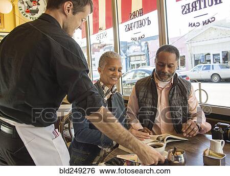 Waiter serving coffee to older couple in coffee shop View Large Photo Image Stock Photograph - Waiter serving coffee to older couple in coffee shop. Fotosearch