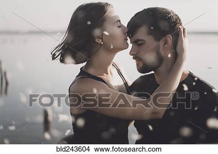Picture - Water splashing on Caucasian couple hugging at lake. Fotosearch