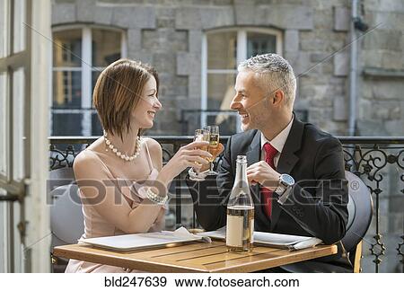 Stock Photo - Well-dressed Caucasian couple toasting with champagne. Fotosearch