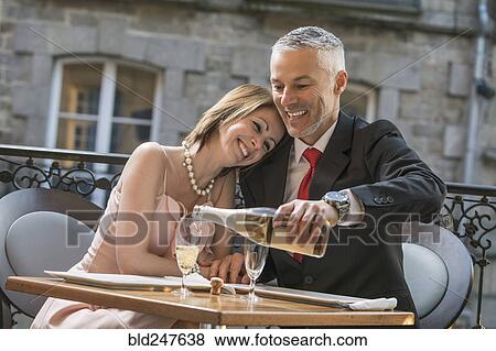 Well-dressed Caucasian man pouring champagne for woman View Large Photo Image Stock Photo - Well-dressed Caucasian man pouring champagne for woman. Fotosearch