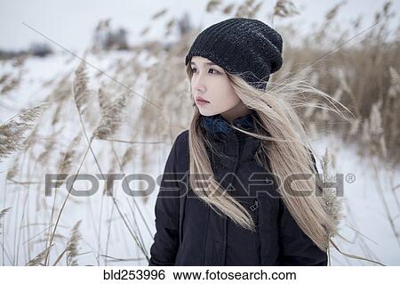 Stock Photograph - Wind blowing hair of Asian teenage girl in winter. Fotosearch