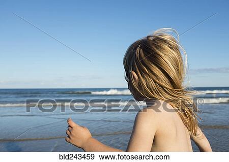 Stock Photo - Wind blowing hair of Caucasian girl on beach. Fotosearch