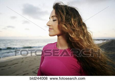 Stock Photo - Wind blowing hair of Caucasian woman on beach. Fotosearch