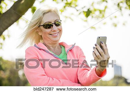 Stock Photo - Wind blowing hair of Caucasian woman texting on cell phone. Fotosearch