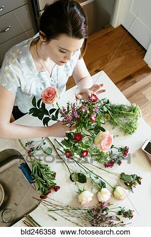 Stock Photo - Woman arranging flowers at table. Fotosearch