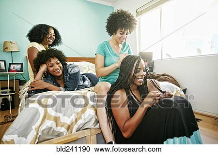 Woman braiding hair of friend in bedroom View Large Photo Image Stock Image - Woman braiding hair of friend in bedroom. Fotosearch