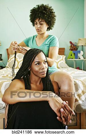 Woman braiding hair of friend in bedroom View Large Photo Image Stock Photograph - Woman braiding hair of friend in bedroom. Fotosearch