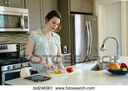 Stock Image - Woman chopping food in domestic kitchen. Fotosearch