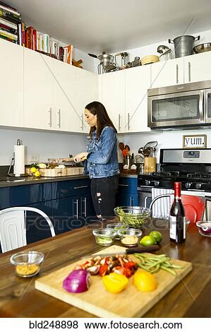 Stock Photo - Woman chopping vegetables in kitchen. Fotosearch