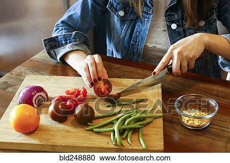 Stock Image - Woman chopping vegetables on cutting board. Fotosearch