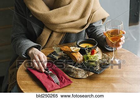 Stock Photography - Woman eating fish with white wine. Fotosearch