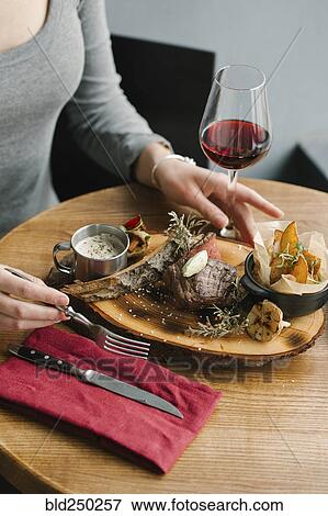 Stock Photo - Woman eating meat with red wine. Fotosearch