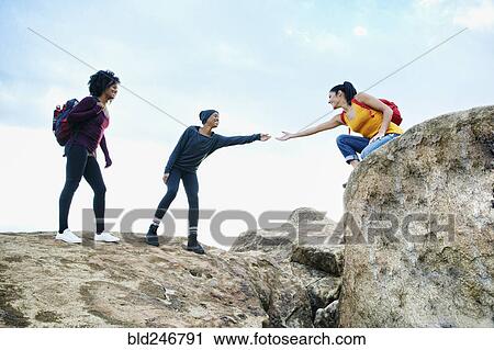 Woman helping friend hiking on rock formation View Large Photo Image Stock Image - Woman helping friend hiking on rock formation. Fotosearch