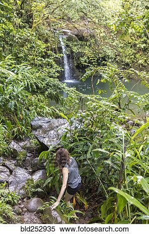 Stock Photography - Woman hiking to remote waterfall. Fotosearch