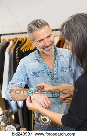 Stock Photo - Woman holding bracelet on wrist of man. Fotosearch