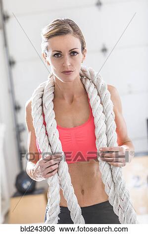 Stock Photo - Woman holding heavy ropes in gymnasium. Fotosearch