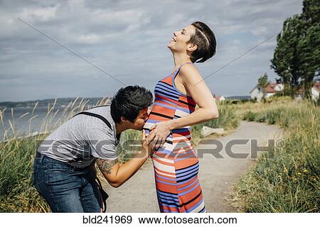 Woman kissing belly of expectant mother View Large Photo Image Stock Photo - Woman kissing belly of expectant mother. Fotosearch
