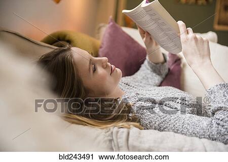 Woman laying on sofa reading book View Large Photo Image Stock Image - Woman laying on sofa reading book. Fotosearch