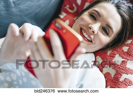 Woman laying on sofa texting on cell phone View Large Photo Image Stock Photograph - Woman laying on sofa texting on cell phone. Fotosearch