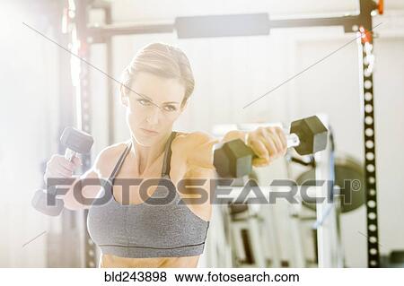 Woman lifting weights in gymnasium View Large Photo Image Stock Photo - Woman lifting weights in gymnasium. Fotosearch