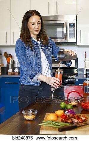 Stock Photography - Woman pouring cocktail in kitchen. Fotosearch