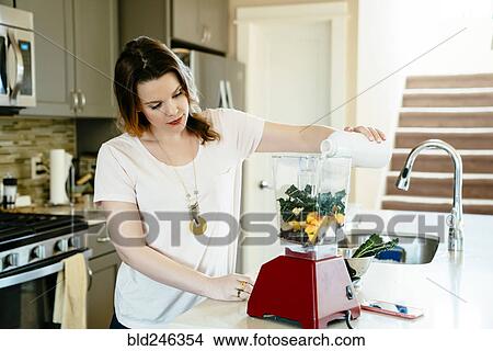 Woman pouring milk into blender with fruit and vegetables View Large Photo Image Picture - Woman pouring milk into blender with fruit and vegetables. Fotosearch