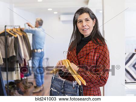 Stock Image - Woman shopping for jeans in clothing store. Fotosearch