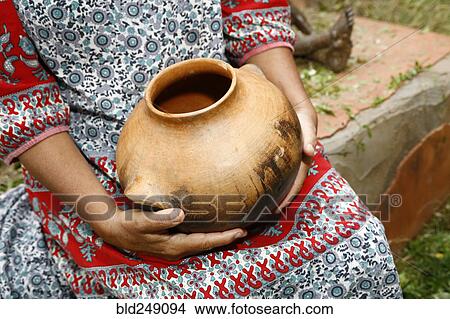 Picture - Woman sitting and holding clay pot. Fotosearch