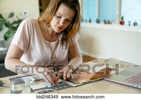 Stock Photo - Woman sitting at table making bow. Fotosearch