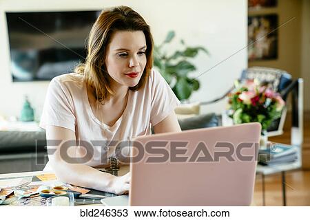 Woman sitting at table using laptop View Large Photo Image Stock Image - Woman sitting at table using laptop. Fotosearch