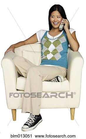 Stock Image - Woman sitting in chair talking on telephone. Fotosearch
