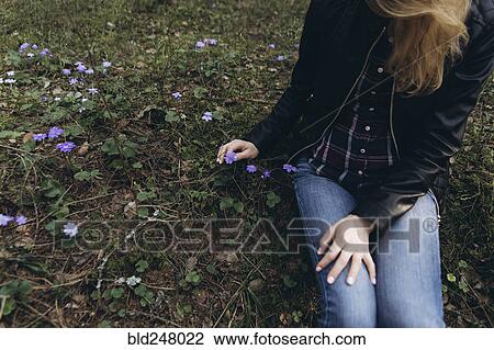 Woman sitting in grass picking purple flower View Large Photo Image Stock Image - Woman sitting in grass picking purple flower. Fotosearch