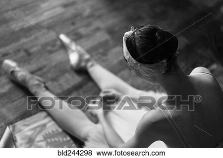 Stock Photo - Woman sitting on floor wearing ballet shoes. Fotosearch