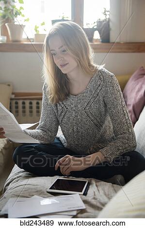 Woman sitting on sofa paying bills with digital tablet View Large Photo Image Stock Photo - Woman sitting on sofa paying bills with digital tablet. Fotosearch