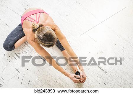 Woman sitting on wooden floor stretching leg View Large Photo Image Stock Image - Woman sitting on wooden floor stretching leg. Fotosearch