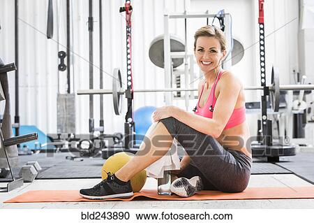 Woman sitting with heavy ball on exercise mat in gymnasium View Large Photo Image Stock Image - Woman sitting with heavy ball on exercise mat in gymnasium. Fotosearch