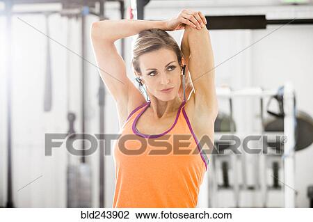 Woman stretching arm in gymnasium View Large Photo Image Stock Image - Woman stretching arm in gymnasium. Fotosearch