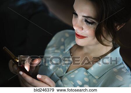 Woman texting on cell phone in the dark View Large Photo Image Stock Photo - Woman texting on cell phone in the dark. Fotosearch