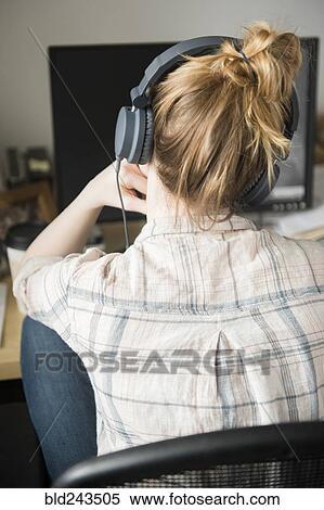 Woman using computer and listening to headphones View Large Photo Image Stock Photography - Woman using computer and listening to headphones. Fotosearch