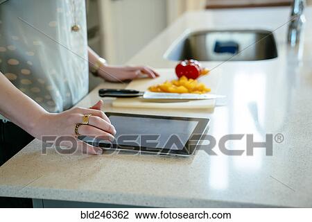 Woman using digital tablet and chopping food in domestic kitchen View Large Photo Image Stock Image - Woman using digital tablet and chopping food in domestic kitchen. Fotosearch